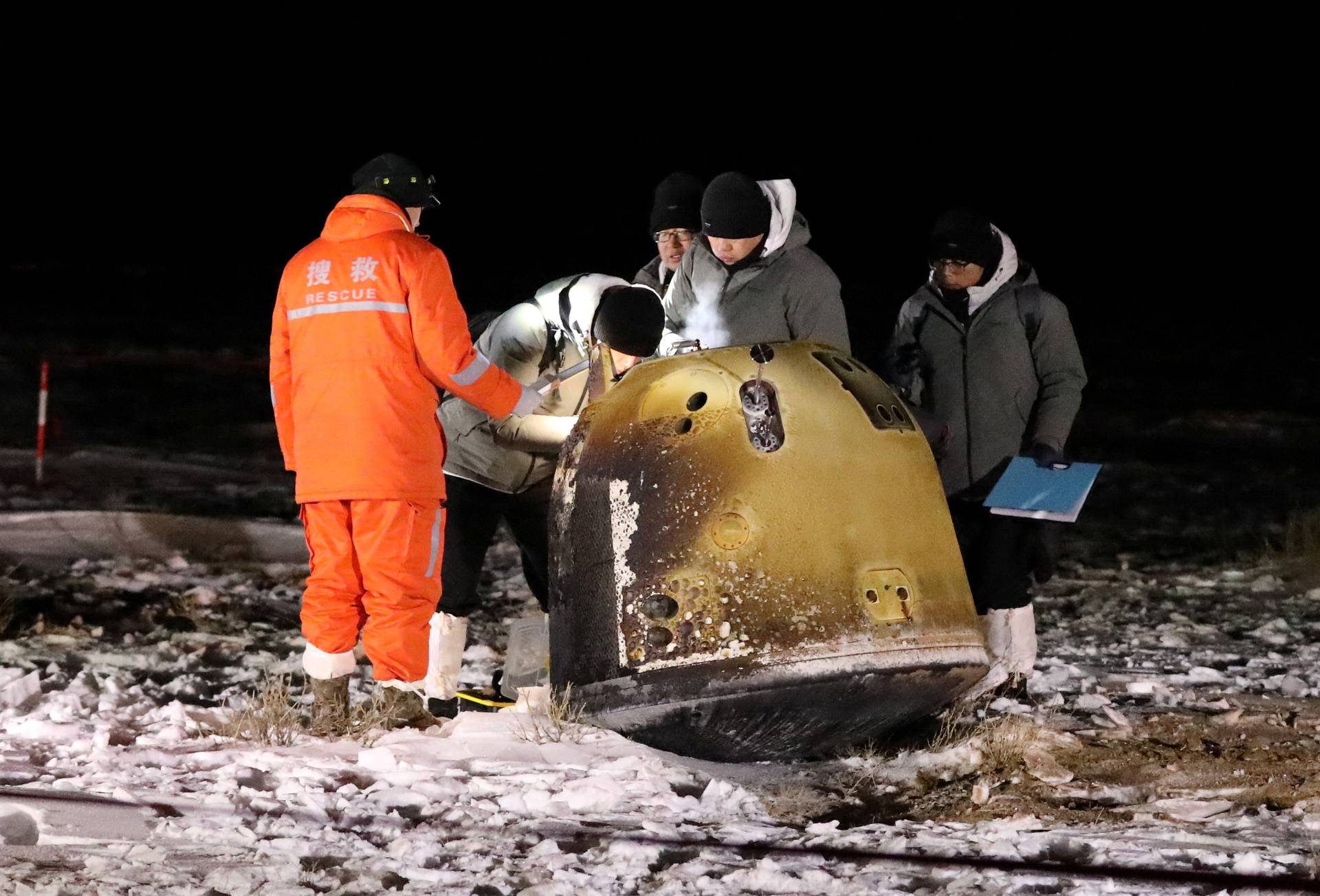 Researchers work next to Chang'e-5 lunar return capsule carrying moon samples, after it landed in northern China's Inner Mongolia Autonomous Region