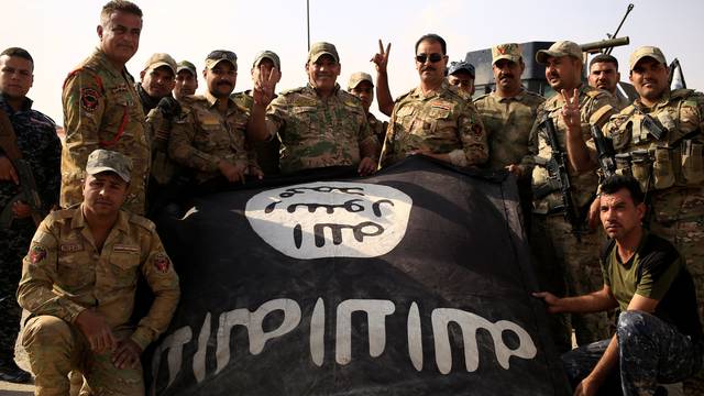 Iraqi soldiers celebrate as they pose with the Islamic State flag along a street of the town of al-Shura