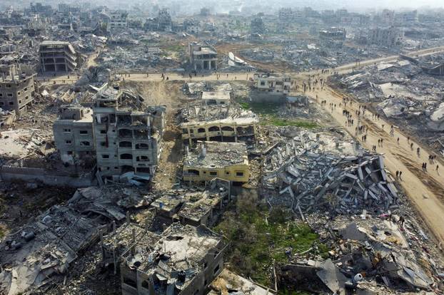 Displaced Palestinians walk past the rubble as they attempt to return to their homes, in the northern Gaza Strip
