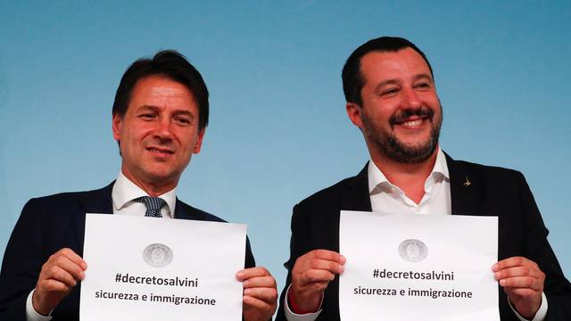 Italy's Prime Minister Conte and Interior Minister Salvini hold up pieces of paper with the name of the new decree written on them during a news conference at Chigi Palace in Rome