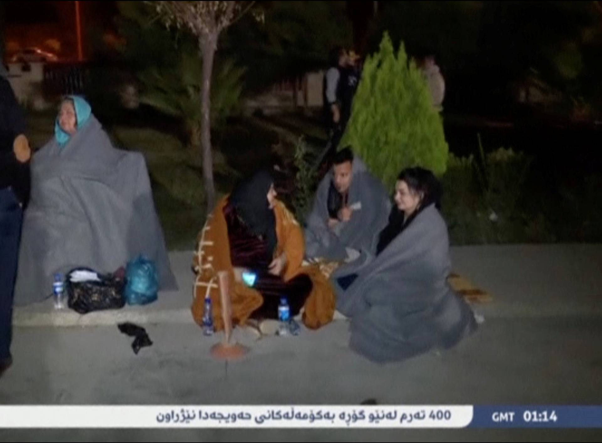 People sit on the pavement after an earthquake at an unknown location in Iraq