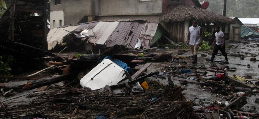 People walk past debris as Hurricane Irma moves off from the northern coast of the Dominican Republic, in Nagua