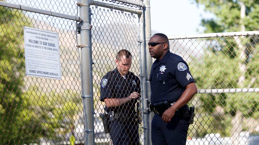 Police officers lock a gate after a shooting at North Park Elementary School in San Bernardino