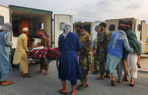 Taliban soldiers and civilians carry earthquake victims to an ambulance at an airport in Jalalabad