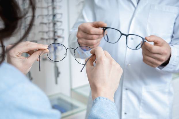 Optic,Shop,Assistant,Showing,Eyeglasses,To,A,Client,In,A