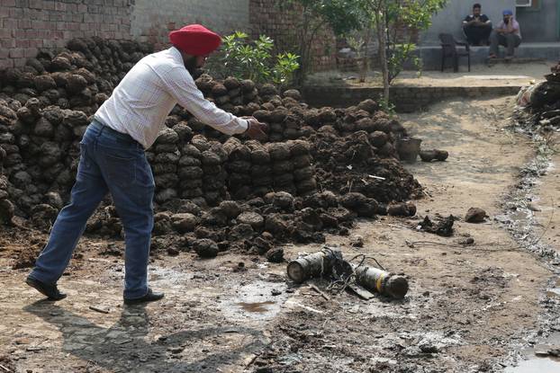 A man takes photographs of projectile debris in a courtyard of a residential house, following Pakistani military strikes, at Wadala Bhitewadh