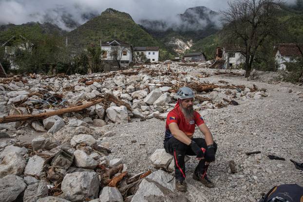 A rescue worker sits among debris following a landslide in the flooded village of Donja Jablanica
