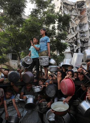 Palestinians wait to receive food from a charity kitchen, amid a hunger crisis, in Gaza City