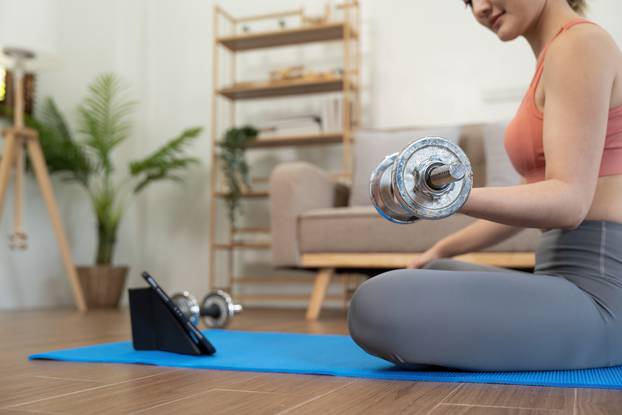 Young woman exercising at tablet having online training at home