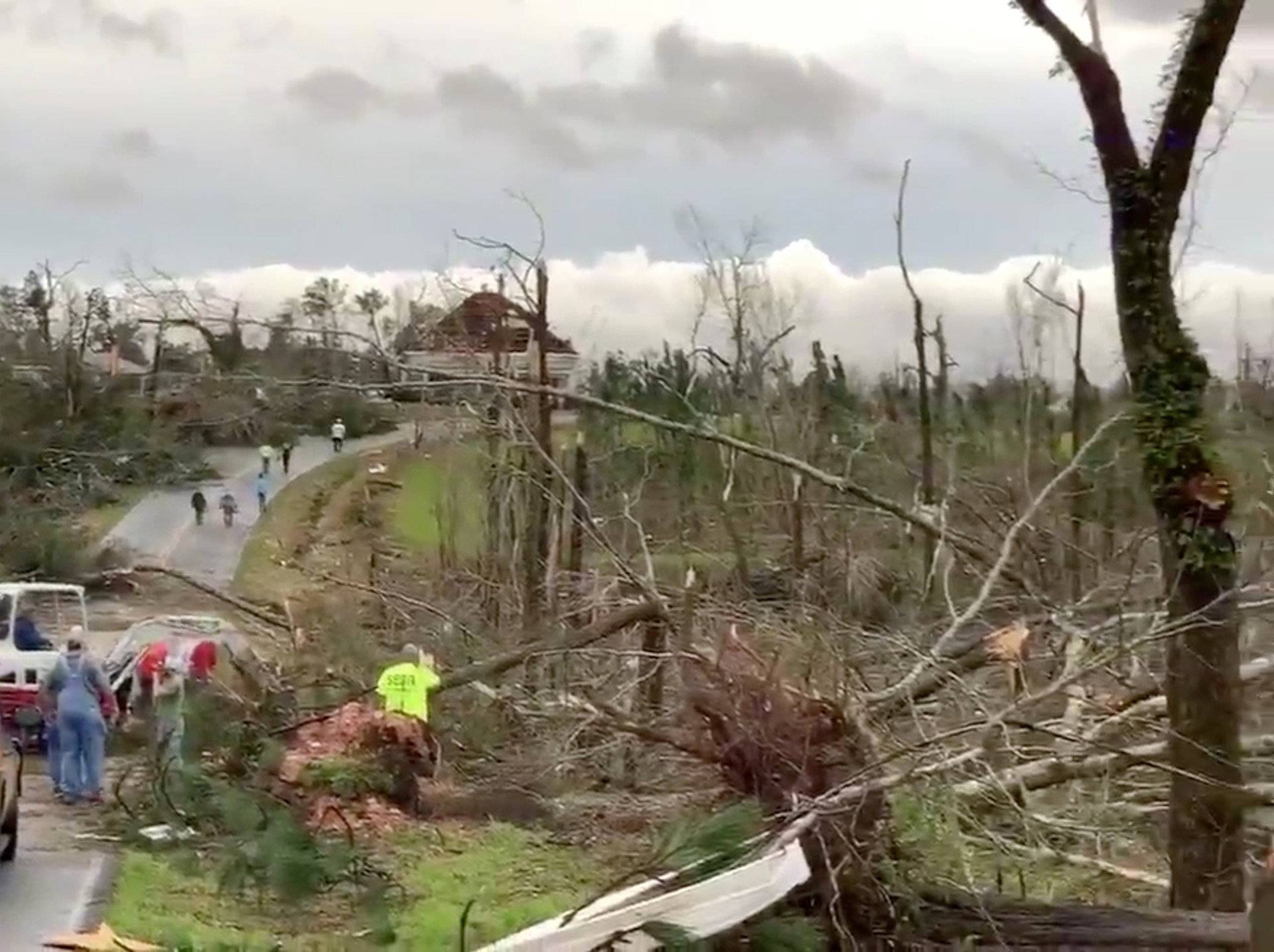 People clear fallen trees and debris on a road following a tornado in Beauregard, Alabama, U.S. in this March 3, 2019 still image obtained from social media video