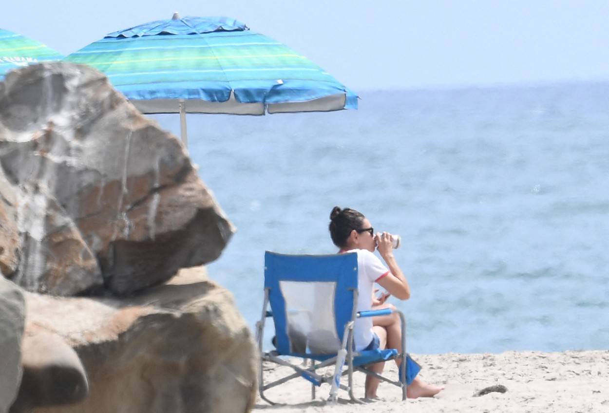 EXCLUSIVE: Mila Kunis hits the beach wearing a T-shirt that reads "Girls Kick Ass" while Ashton Kutcher sports a bright orange Peloton shirt