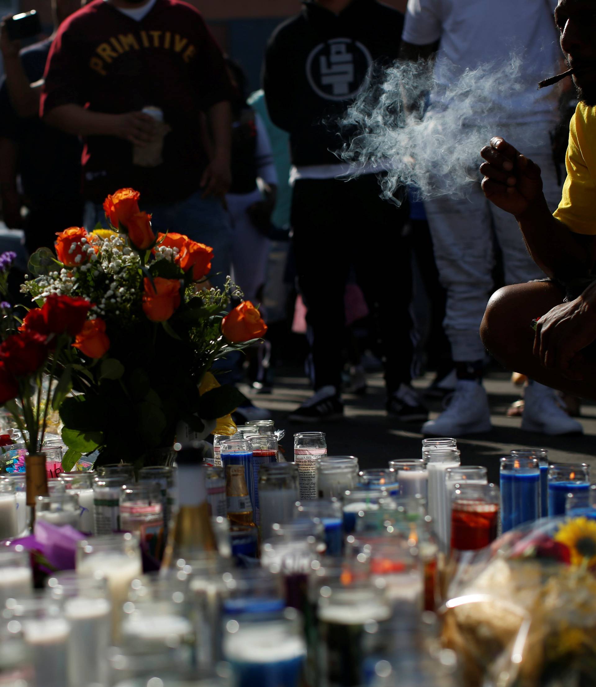 A person smokes by a makeshift memorial for Grammy-nominated rapper Nipsey Hussle who was shot and killed outside his clothing store in Los Angeles
