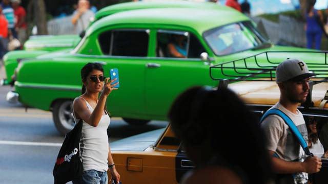 A woman uses the internet on her mobile phone at a hotspot in Havana, Cuba