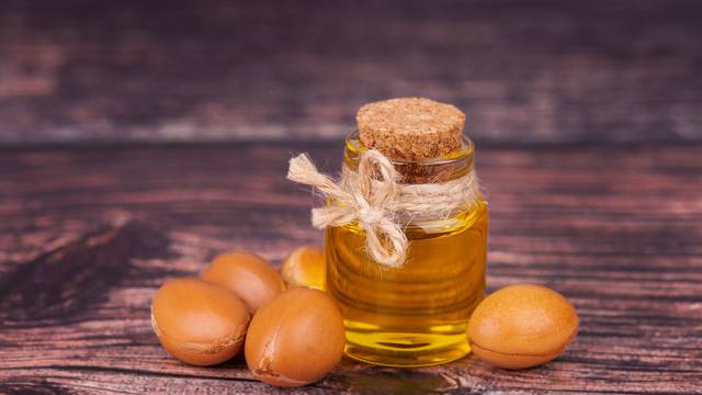 Argan oil on wooden background. Argan nuts and seeds, for cosmetic and beauty products. Natural argan fruit from Morocco.