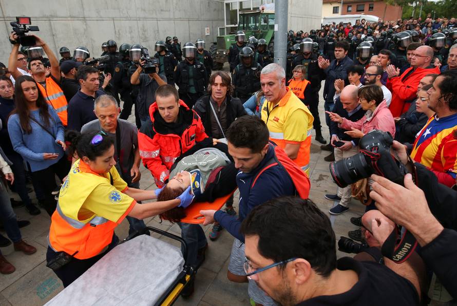 Woman is carried onto stretcher by ambulance crew outside Catalonia referendum polling station in Sant Julia de Ramis
