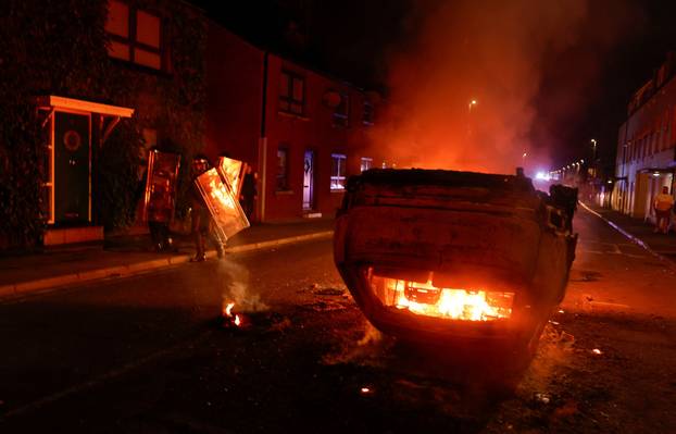 Armed police in riot gear stand guard during a second night of riots, in Ballymena