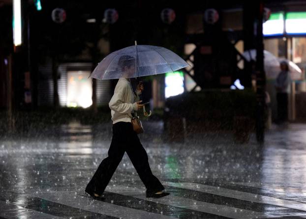A woman crosses a street in heavy rain as a result of Typhoon Dujuan in Tokyo