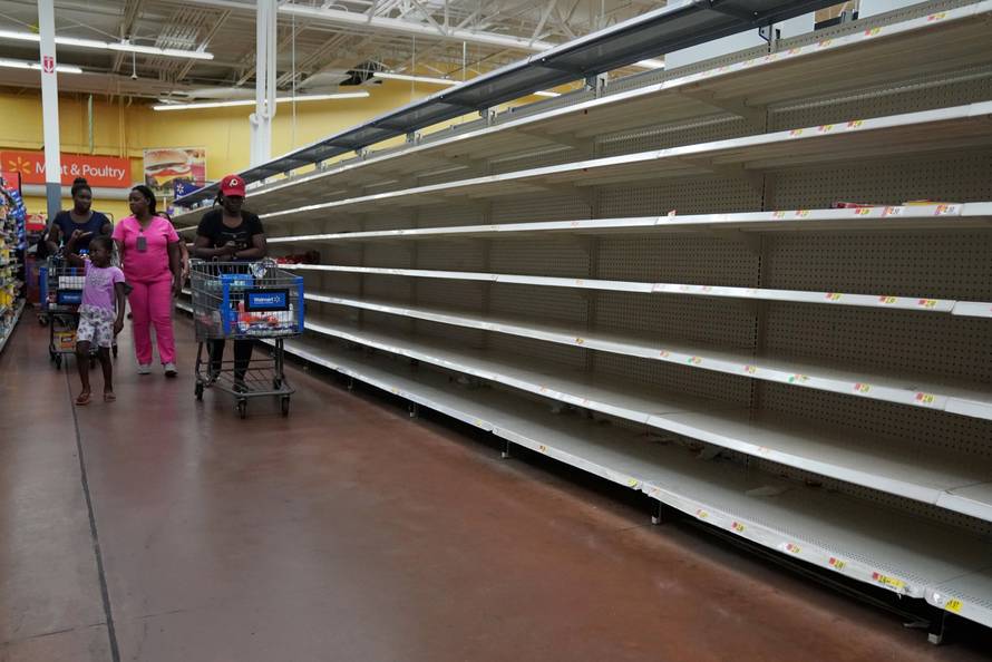 People walk past empty shelves where bread is normally sold in a Walmart store in advance of Hurricane Irma's expected arrival in North Miami Beach