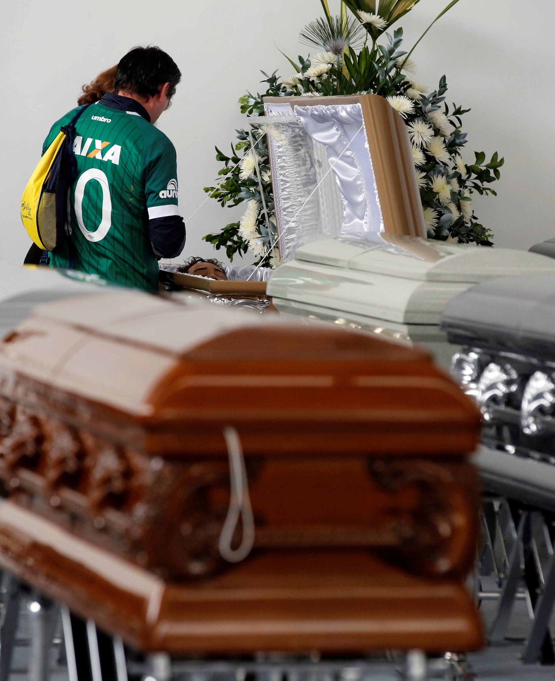 A relative looks into the coffin of Nilson Folle Junior, one of the soccer team's managers and who died along with others in an accident of the plane that crashed into the Colombian jungle with the Brazilian soccer team onboard, in Medellin