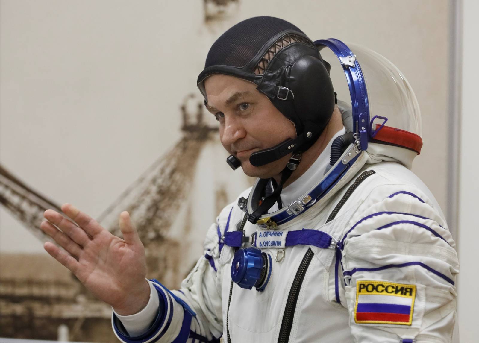 The International Space Station (ISS) crew member Aleksey Ovchinin of Russia waves before his space suit check at the Baikonur Cosmodrome