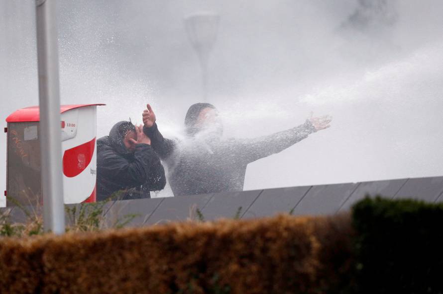 Far-right supporters are sprayed with a water cannon during a protest against Marrakesh Migration Pact in Brussels