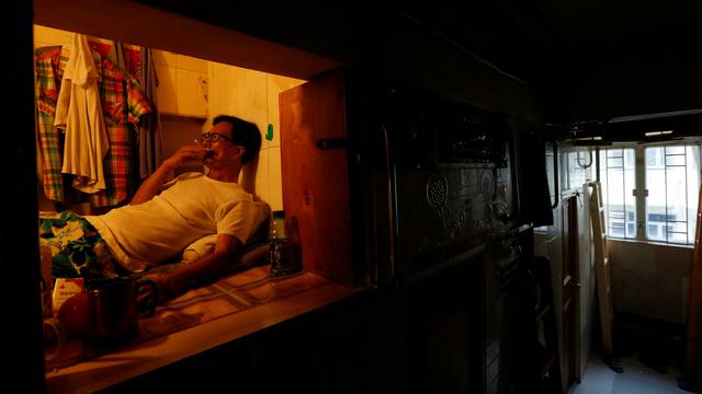 Unemployed Hong Kong resident Simon Wong, 61, smokes inside his 4-by-6-feet partitioned unit, or "coffin unit", with a monthly rent of HK$1,750 ($226) in Hong Kong