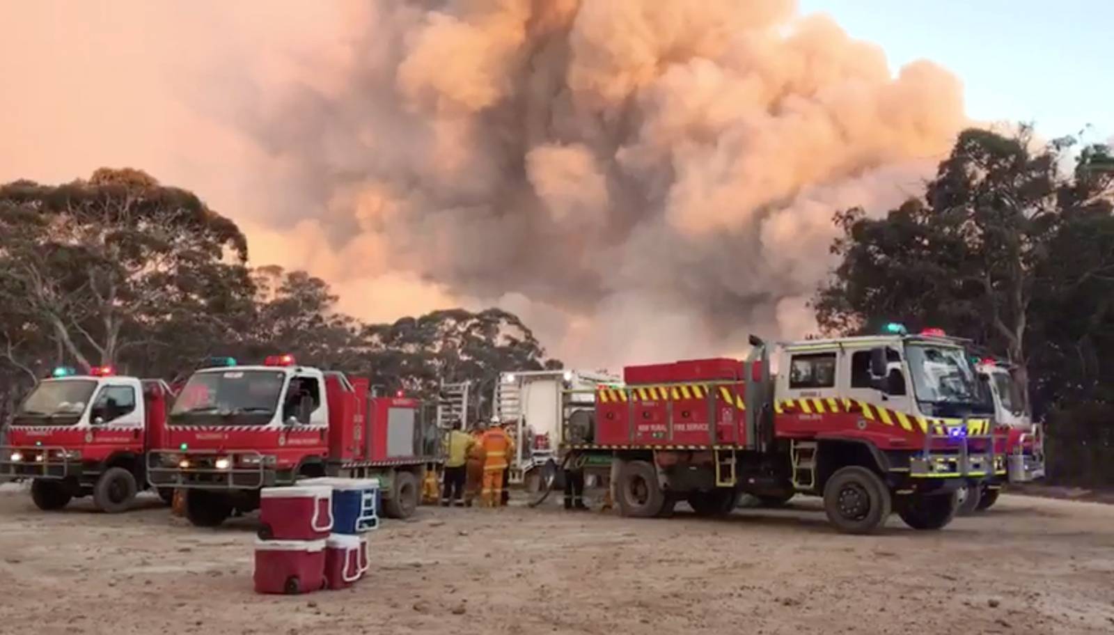 Smoke of fire rise next to firefighting vehicles as bushfires burn in Newnes Plateau