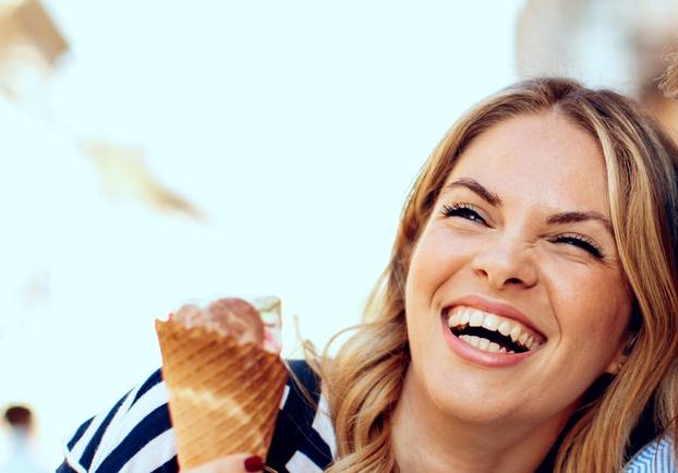 Two young women laughing and holding ice cream in hand
