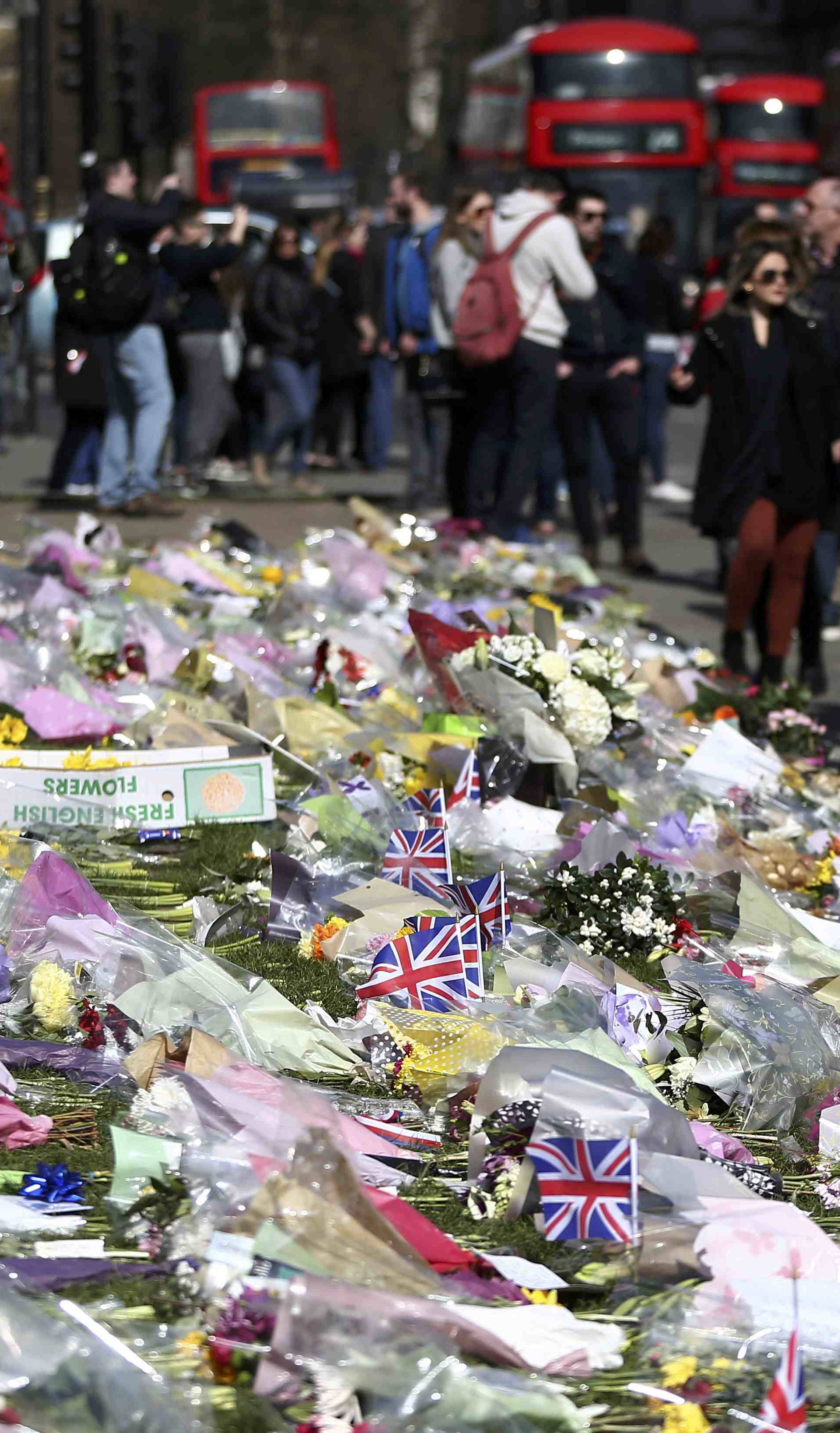 Onlookers view floral tributes laid in Parliament Square following the attack in Westminster earlier in the week