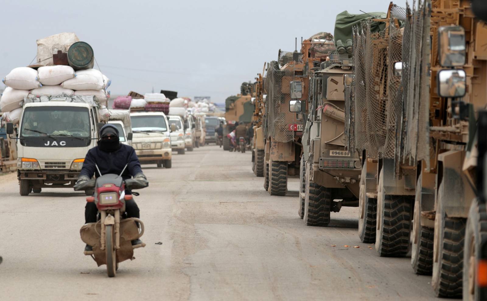 A man rides on a motorbike past Turkish military vehicles in Hazano near Idlib