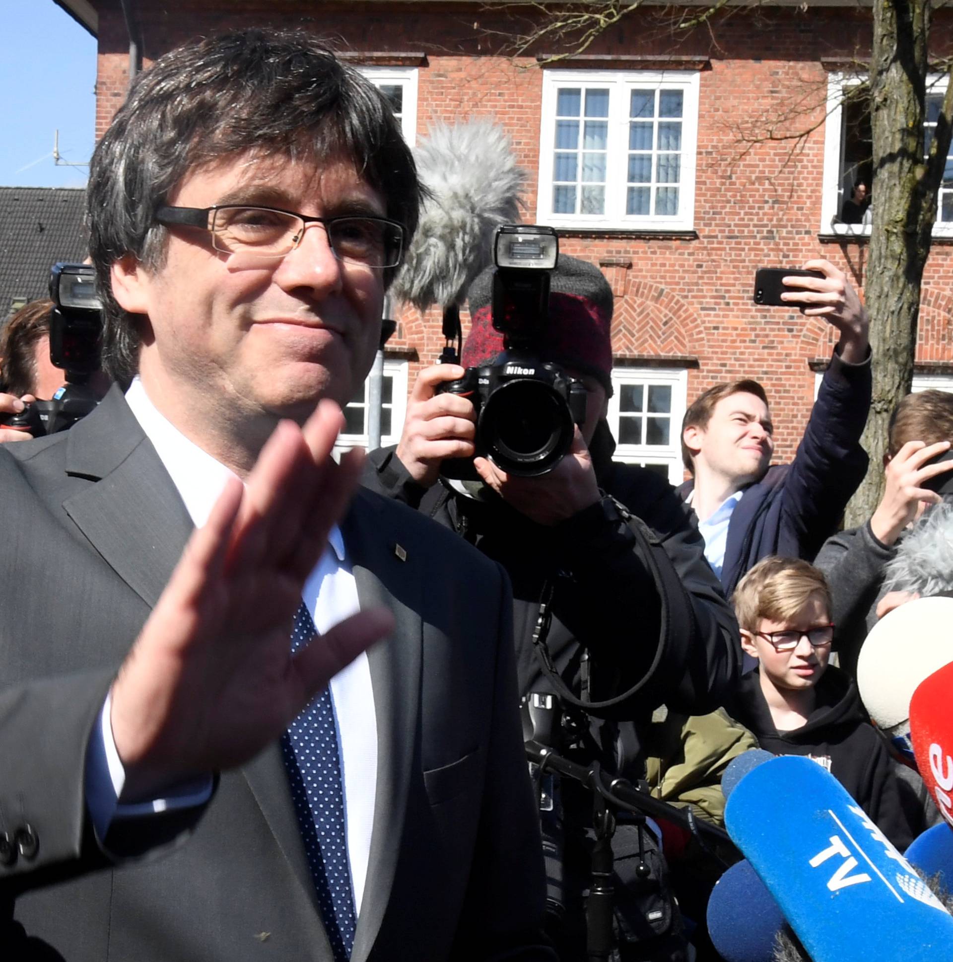 Catalonia's former leader Carles Puigdemont waves to the media as he leaves the prison in Neumuenster