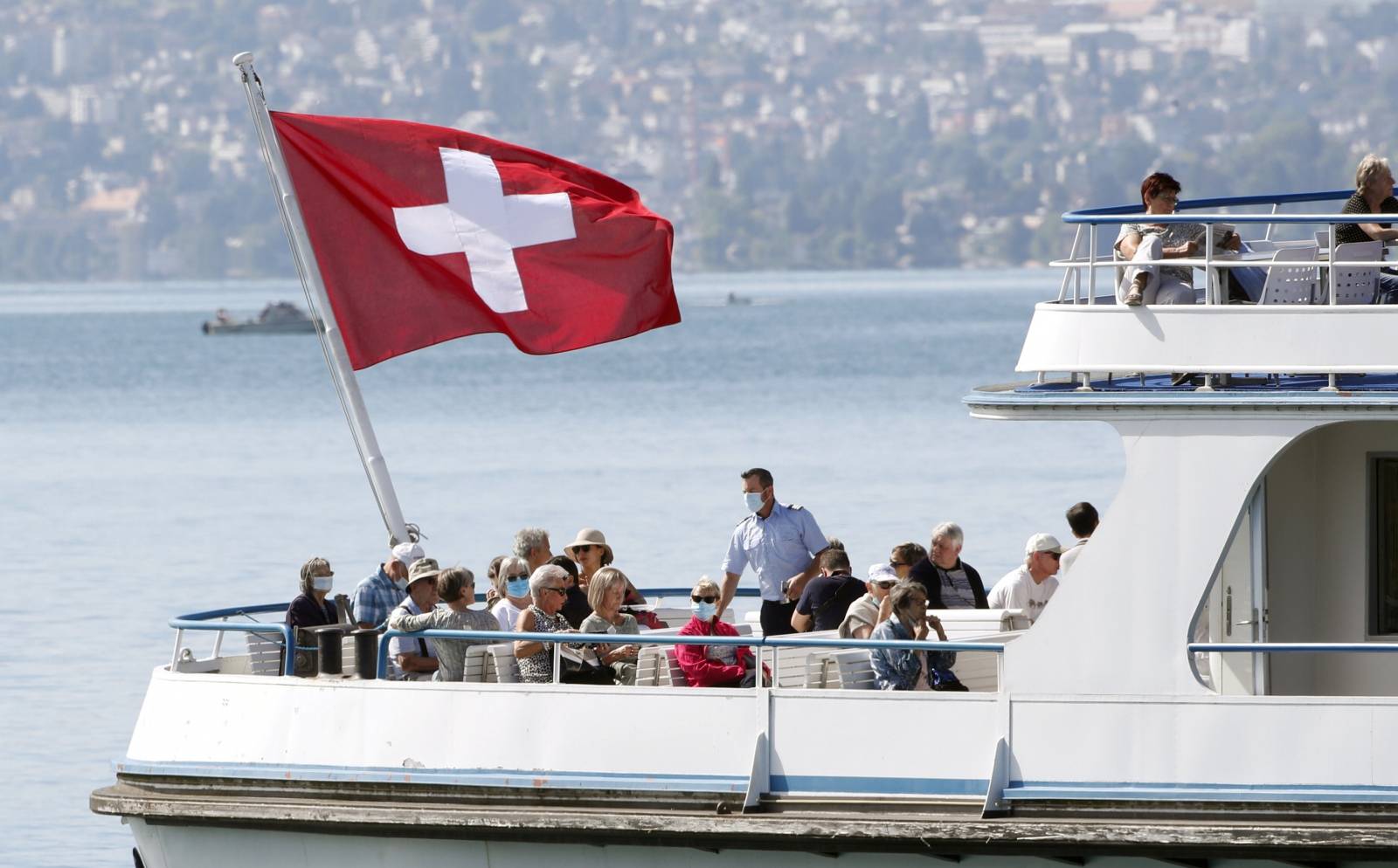 Switzerland's national flag flies above passengers as tourist vessel Limmat sails on Lake Zurich in Zurich