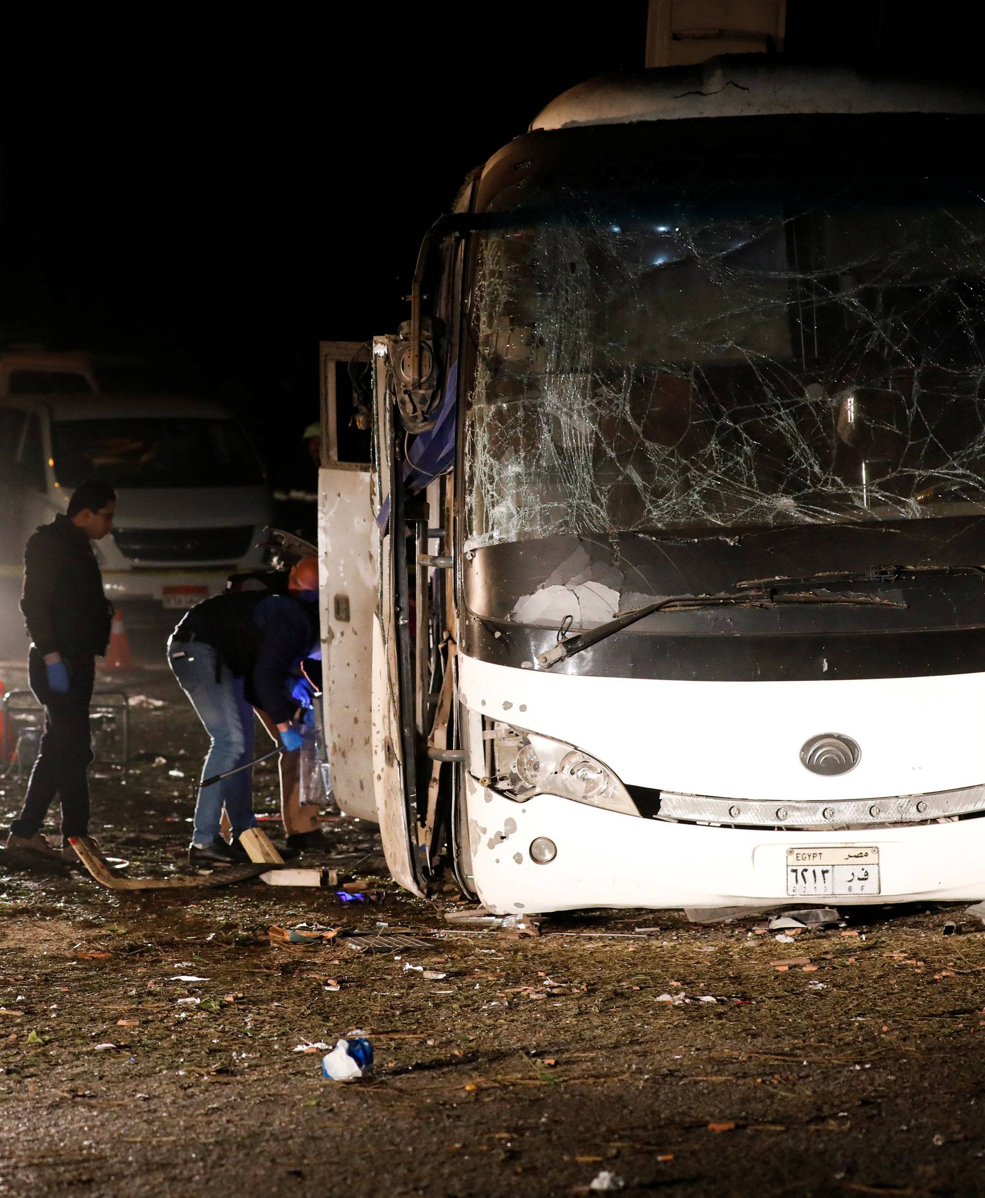 Police officers inspect a scene of a bus blast in Giza