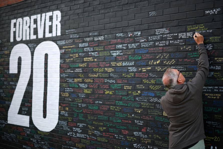 FILE PHOTO: A fan adds a message to a memorial wall created near Anfield Stadium following the death of Liverpool soccer player Diogo Jota in Liverpool
