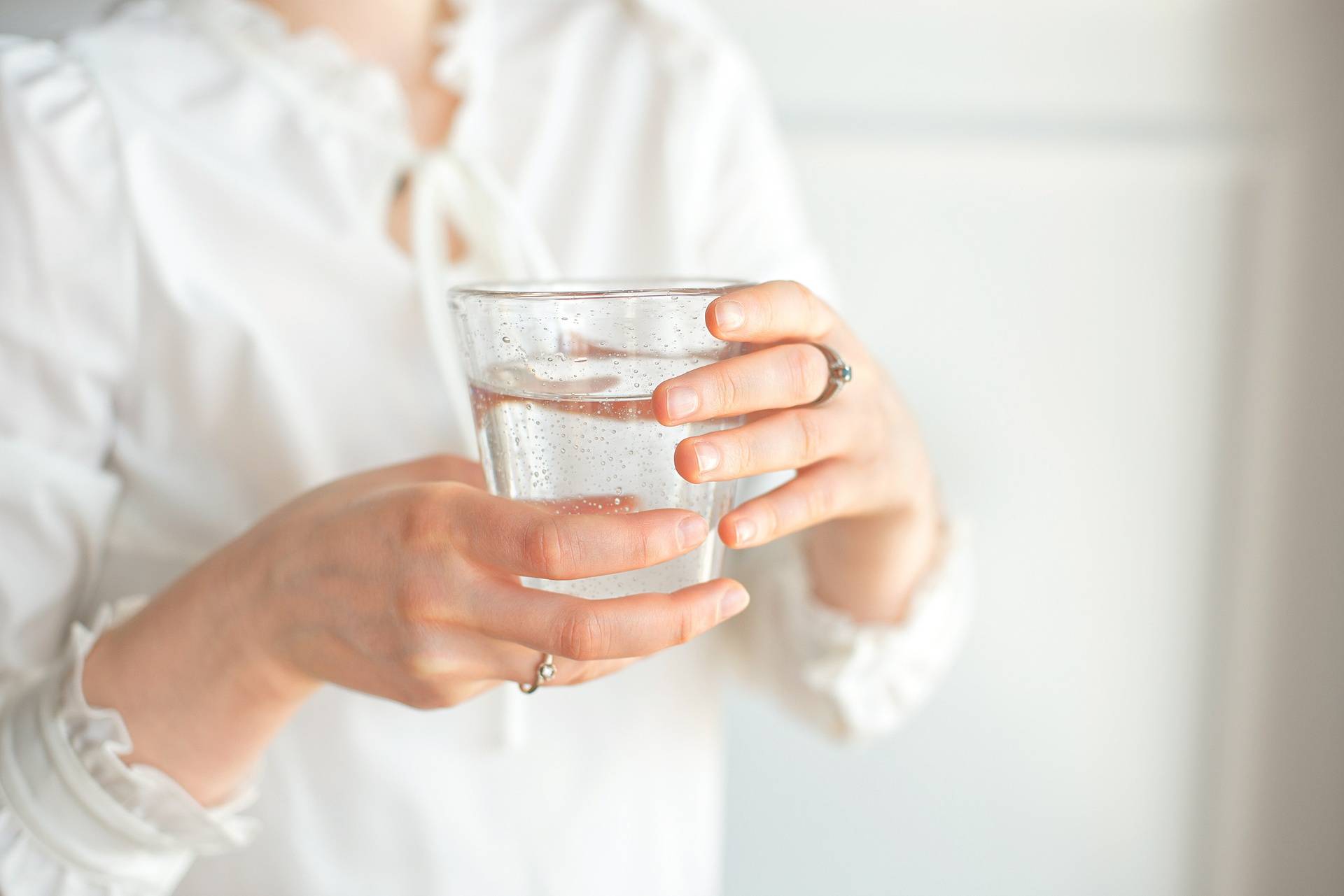 Glass of clean mineral water in woman's hands. Concept of environment protection, healthy drink