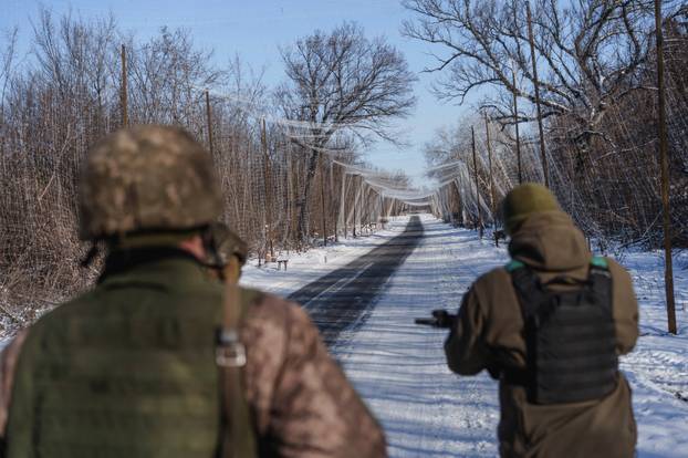 Ukrainian servicemen walk along a street under an anti-drone net near a front line in Donetsk region
