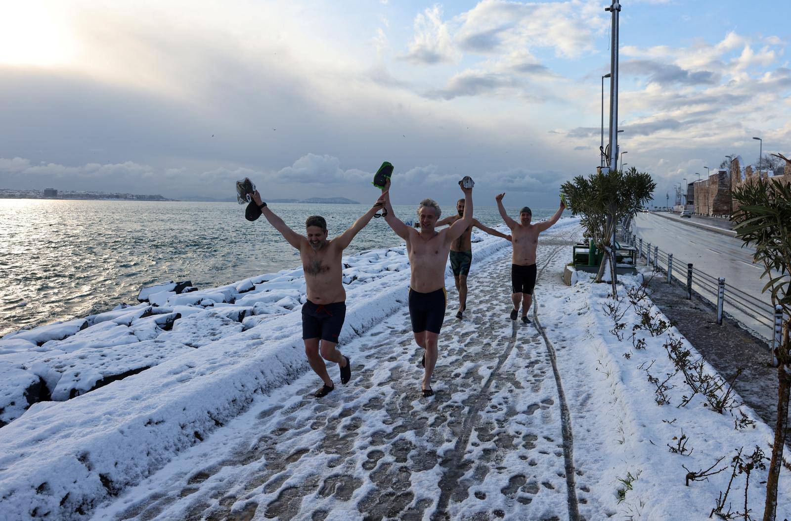 A group of swimmers run to warm-up before they dive into the chilly waters of the Bosphorus on a snowy day in Istanbul