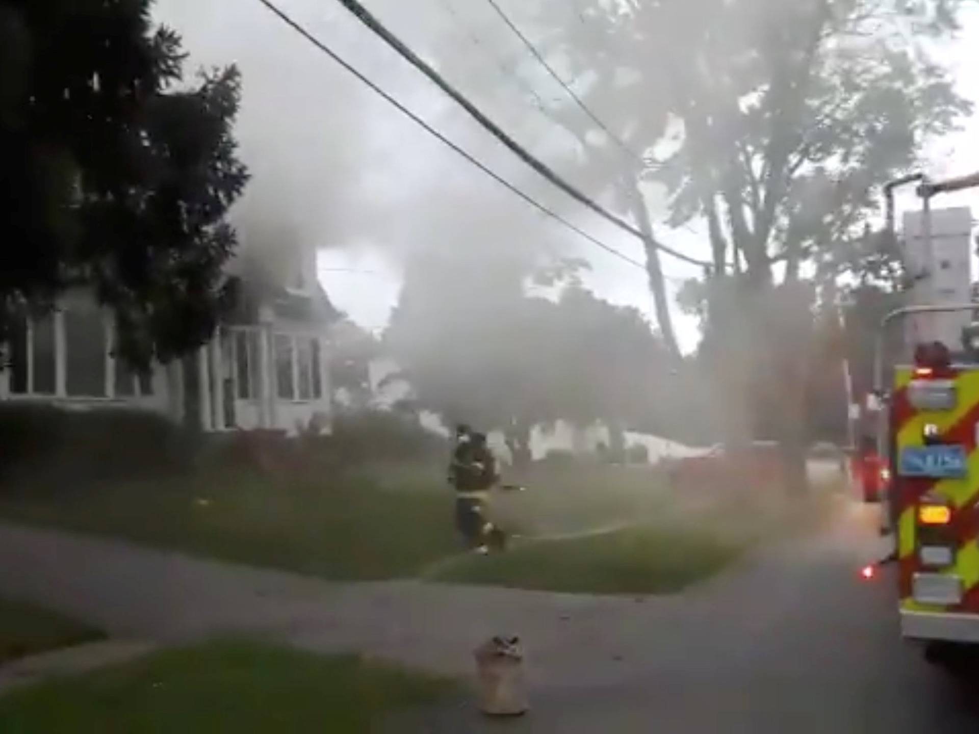 Still image from social media video footage by Boston Sparks shows firefighters working near a building emitting smoke after explosions in North Andover, Massachusetts