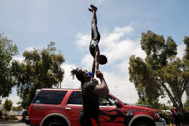 Circus performers intertain kids and parents in food bank drive therough line in San Diego