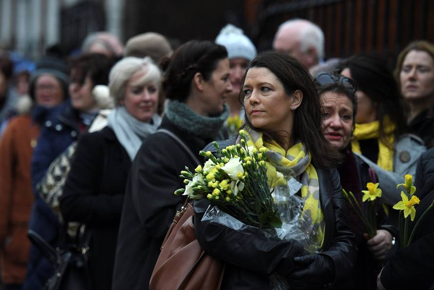 Schoolfriends bring yellow flowers to represent sunshine as they queue up to view Cranberries singer Dolores O'Riordan's coffin as it is carried into St. Joseph's Church for a public reposal in Limerick