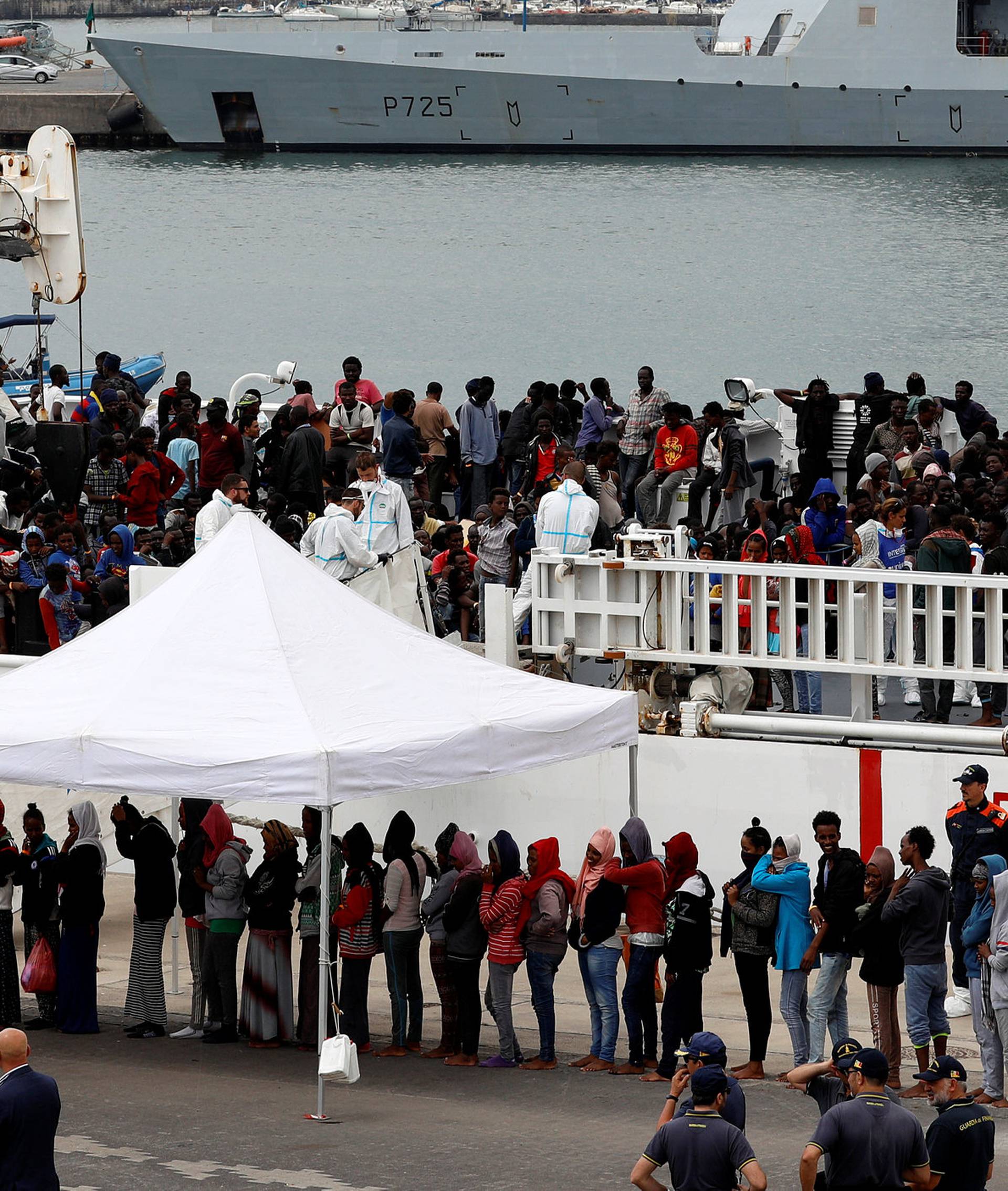 Migrants disembark Italian coast guard vessel "Diciotti" as they arrive at the port of Catania