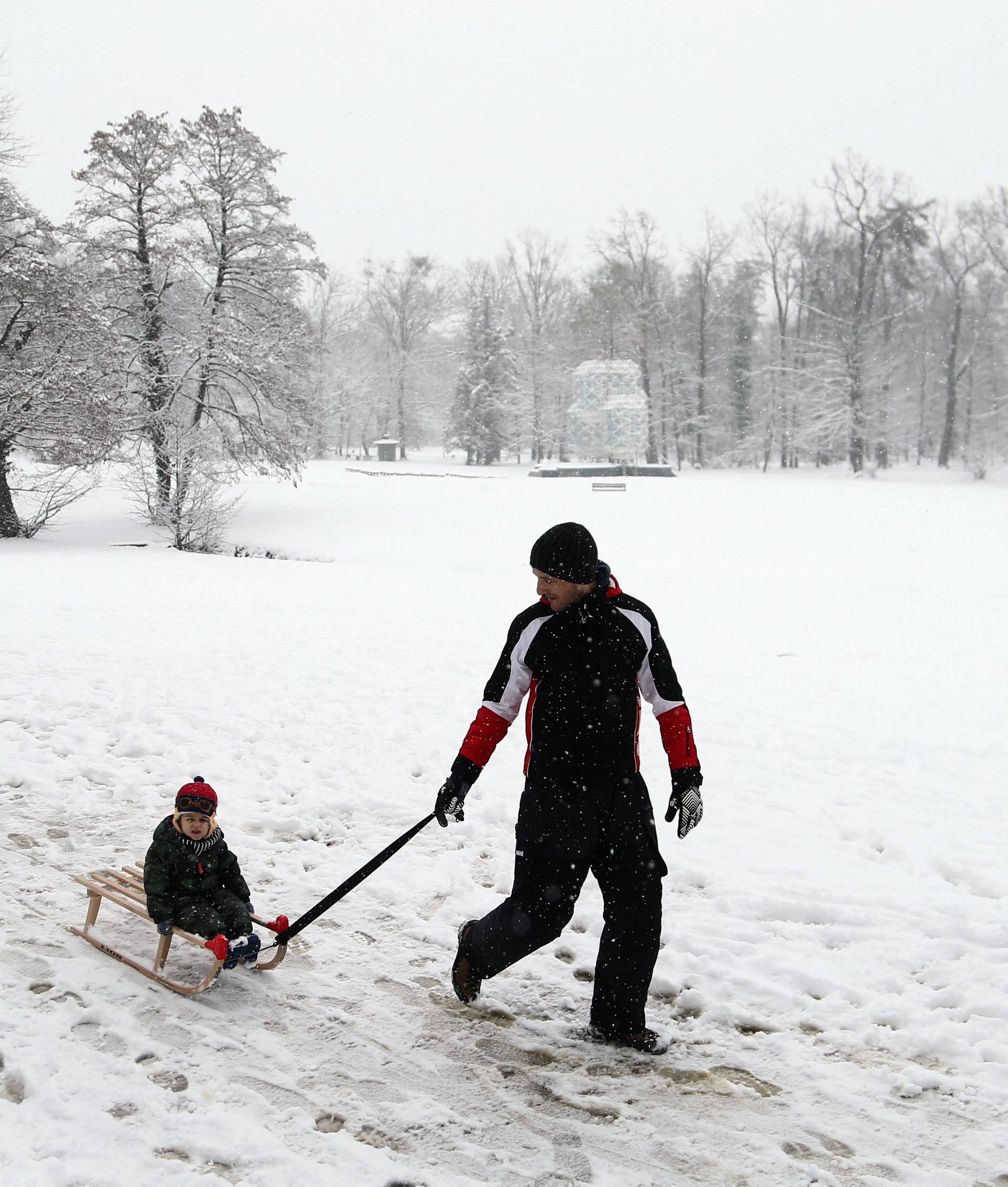 A man walks with a boy under the falling snow in Zagreb's park Maksimir
