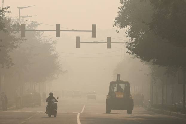 A bulldozer is seen on a road, on a smoggy morning, in New Delhi