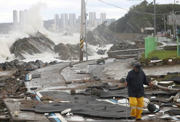 A man walks on a road along the coast damaged by Typhoon Hinnamnor in Ulsan