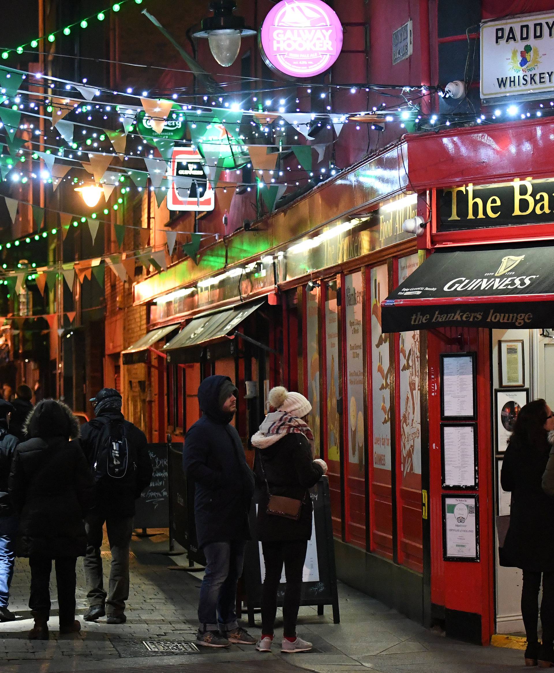 People walk under Christmas lights illuminating a street in Dublin