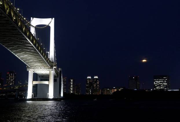 A supermoon, the biggest and brightest full moon of the year, rises through clouds above Odaiba of Tokyo