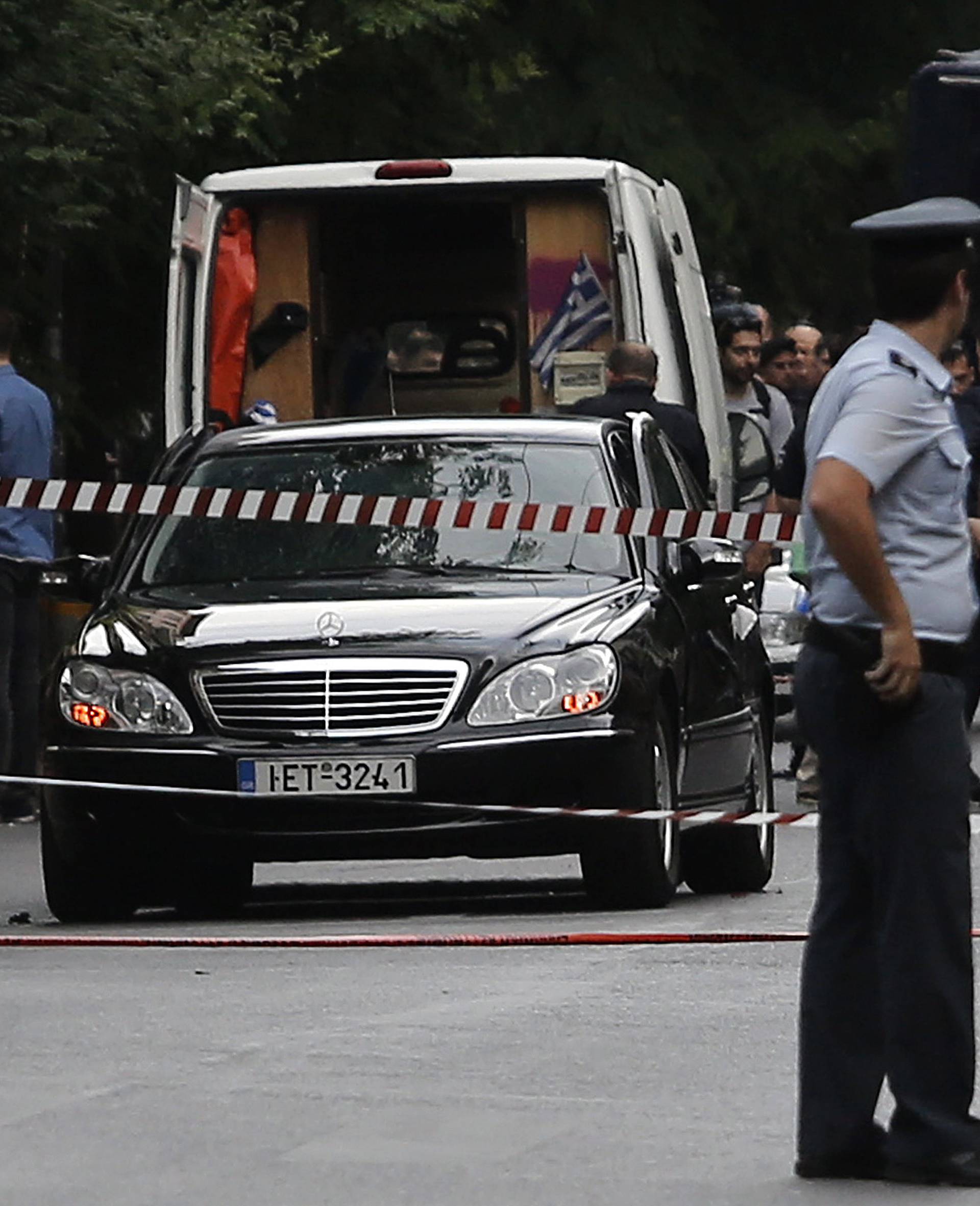 Police secure the area around the car of former Greek prime minister and former central bank chief Lucas Papademos following the detonation of an envelope injuring him and his driver, in Athens