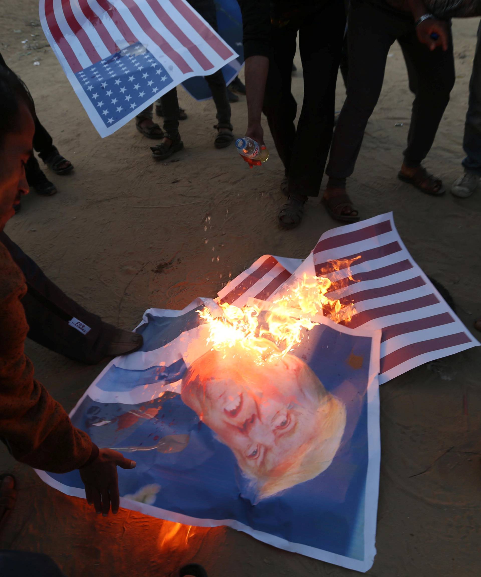 Palestinian demonstrators burn representations of U.S. flags and a poster of U.S. President Trump during a protest, at the Israel-Gaza border in the southern Gaza Strip