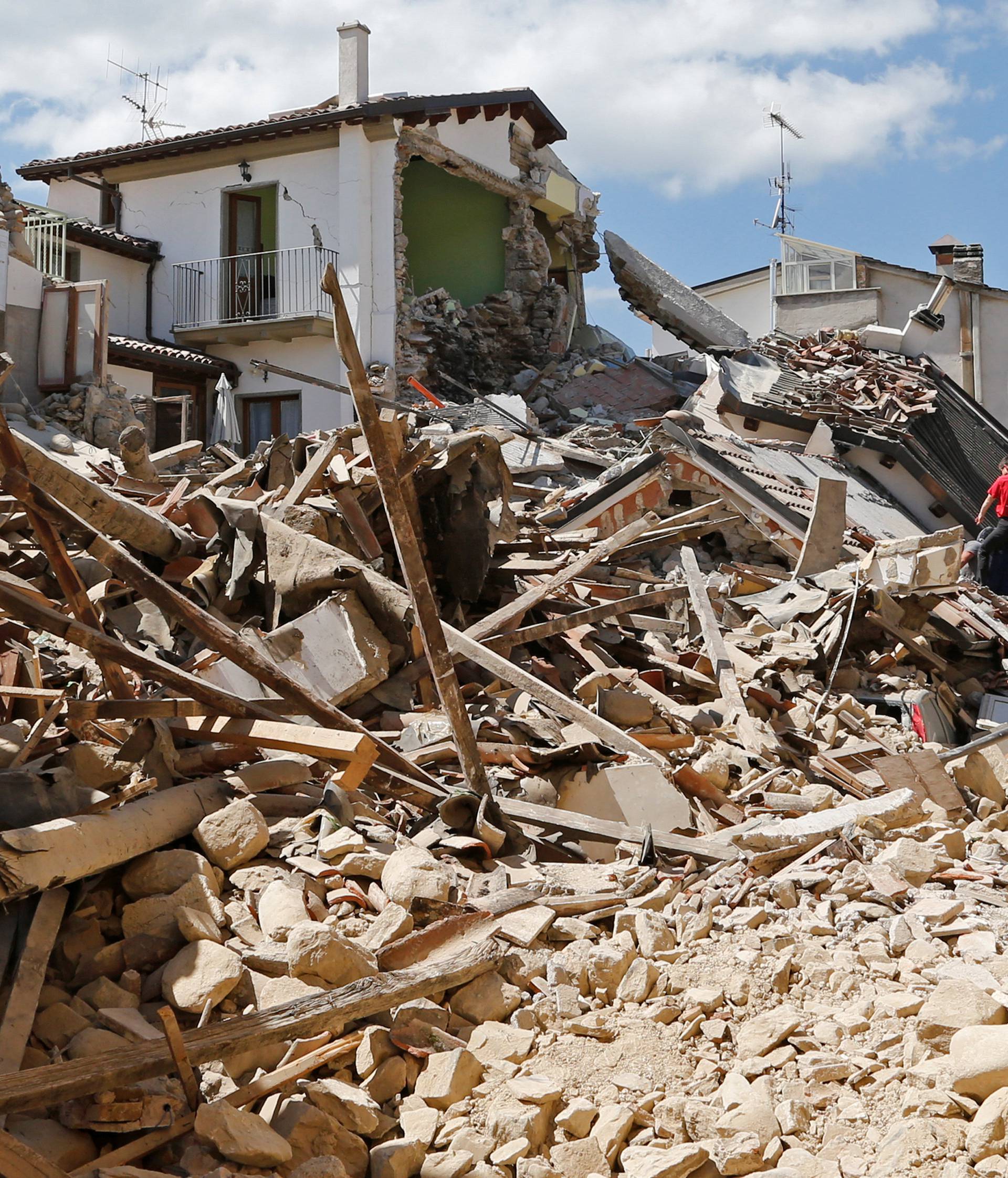 People and rescuers stand next collapsed buildings following an earthquake in Amatrice
