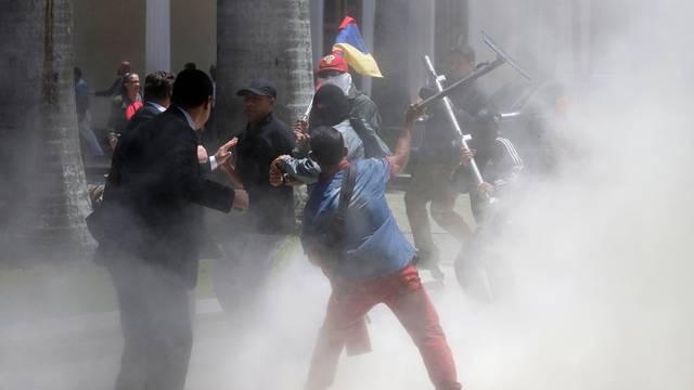 Government supporters hold a national flag while clashing with people outside the National Assembly, in Caracas